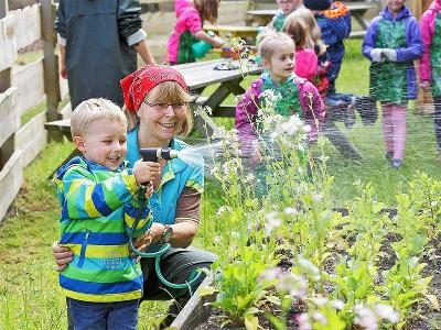 Kinder im Hotelgarten gießen Blumen im Familienurlaub Niedersachsen