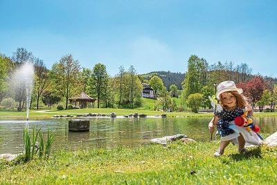 Kind am Teich mit viel Grün umgeben im Familienurlaub Deutschland