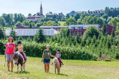 Kinder mit ihren Eltern auf Ponys im Familienurlaub Bayern