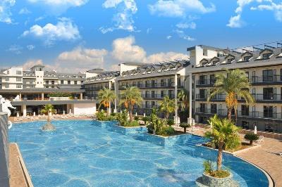Pool mit mehreren Palmen und Hotelgebäude umgeben im Familienurlaub Türkei