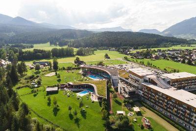 Hotelanlage mit Pools, grünen Wiesen und umgeben von Bergen im Familienurlaub Österreich