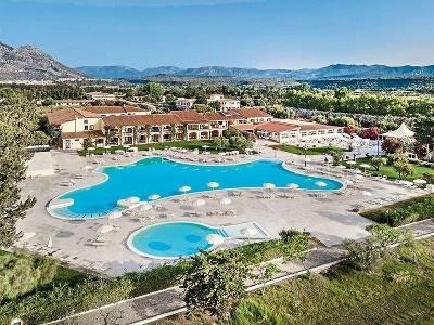 Zwei Pools umgeben von Hotel und Bergen im Familienurlaub Sardinien