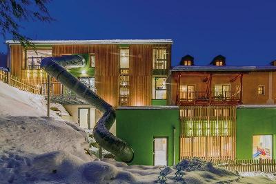 Hotel mit Holzfassade und geschwungener Rutsche im Familienurlaub Deutschland