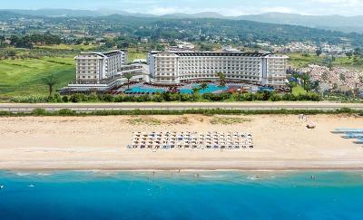 Breiter Sandstrand mit Liegen und großer Hotelanlage im Hintergrund im Familienurlaub Türkei