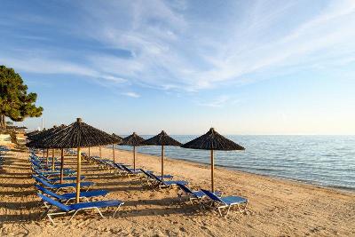 Blaue Sonnenliegen mit Schirmen am Strand beim Familienurlaub Griechenland