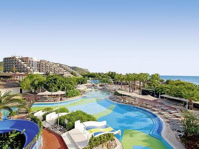 Blau-grüner Pool mit Wasserrutschen und Blick aufs Meer im Familienurlaub Türkei