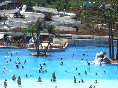 Menschen im Pool vor großer Wasserrutsche im Familienurlaub Spanien