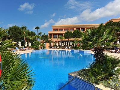Flaches Hotelgebäude am Pool mit Palmen im Familienurlaub Spanien