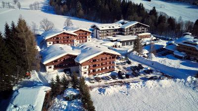 Verschneite Hotelanlage mit mehreren Häusern im Familienurlaub Österreich