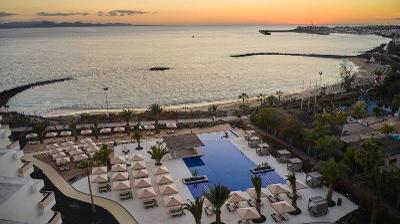 Blick aus einem oberen Stockwerk auf den Pool und den direkt angrenzenden Strand im Familienurlaub Kanaren