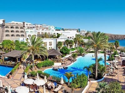 Gemütliche Anlage mit vielen Palmen, die im Pool Schatten spenden im Familienurlaub Lanzarote