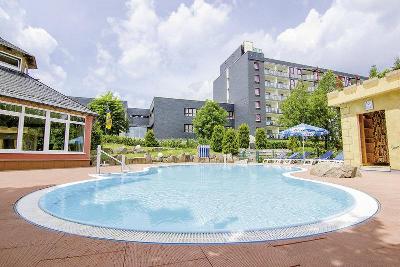 Mehrstöckiges Hotelgebäude mit einfachem Pool und Liegen im Familienurlaub Thüringen