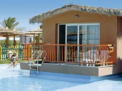 Frau liest ein Buch am Bungalow mit direktem Poolzugang im Familienurlaub Ägypten