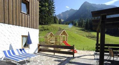 Terrasse mit kleinem Spielplatz umgeben von Bergen im Familienurlaub Österreich