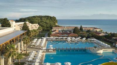 Zwei Pools mit weißen Sonnenschirmen und Meer im Familienurlaub Griechenland