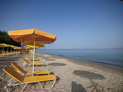 Gelbe Sonnenliegen mit Schirmen am Sandstrand im Familienurlaub Kos