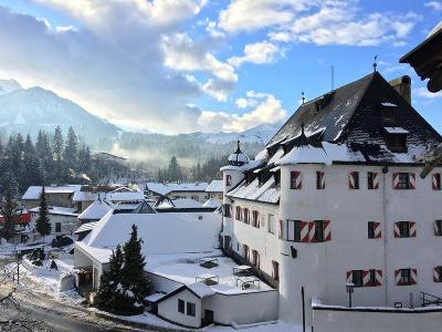 Hotel vor den Bergen mit Nadelwald und Schnee im Familienurlaub Österreich