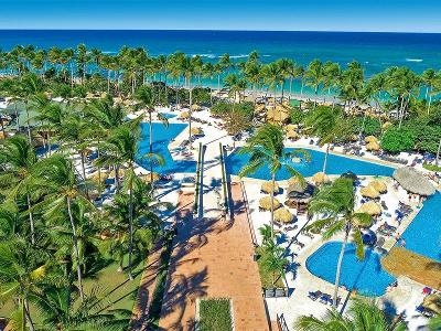 Palmen im Wind vor dem Meer mit vielen Pools im Familienurlaub Dominikanische Republik