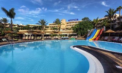 Gebogener Pool mit drei bunten Rutschen im Familienurlaub Spanien