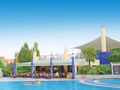 Mann auf Luftmatratze im Pool im Familienurlaub Italien