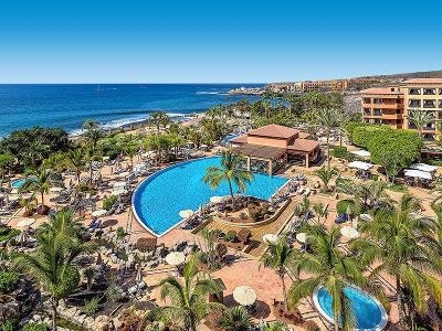 Weitläufige Poolanlage mit Palmen und Steinen am Meer im Familienurlaub Spanien