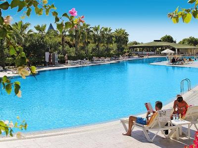 Mann liest Zeitung am Pool im Familienurlaub Türkei