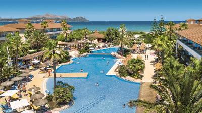 Pool mit Personen und von Palmen umgeben im Familienurlaub Mallorca