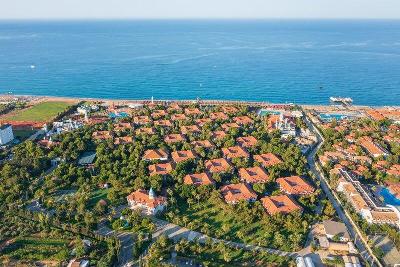 Mehrere Häuser umgeben von Bäumen mit direkter Verbindung zum Strand im Familienurlaub Türkei