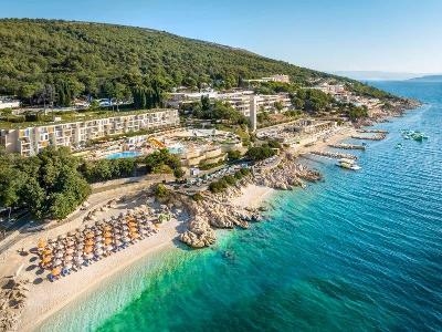 Klares Meer mit Felsen und Sonnenliegen vor dem Hotel im Familienurlaub Kroatien