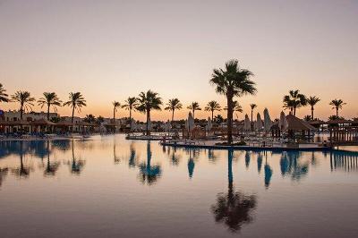 Poolanlage mit Palmen bei Sonnenuntergang im Familienurlaub Ägypten