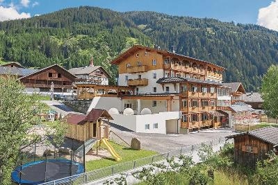 Spielplatz mit Trampolin und urigem Hotelgebäude im Familienurlaub Österreich