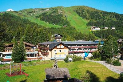 Hotel vor grünem Berg im Familienurlaub Österreich