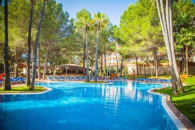 Pool und rundherum grün mit vielen Palmen im Familienurlaub Spanien