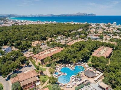 Dreiteiliger Pool umgeben von Hotelgebäuden und Waldstück im Familienurlaub Spanien