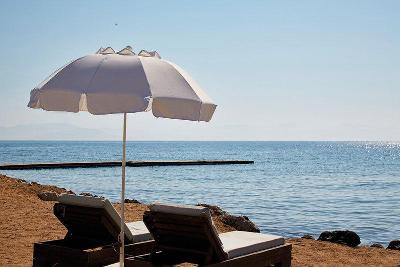 Zwei bequeme Liegen mit Sonnenschirm direkt am Strand im Familienurlaub Korfu