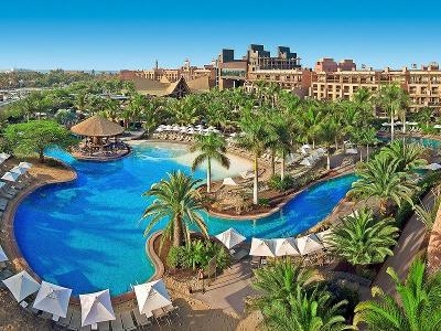 Geschwungener Pool mit vielen Palmen im Familienurlaub Spanien