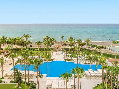 Pool mit Palmen und direktem Zugang zum Meer im Familienurlaub Spanien