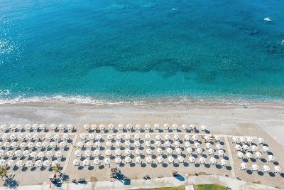 Sonnenliegen mit Schirmen am Sandstrand im Familienurlaub Griechenland
