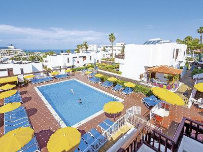 Rechteckigen Hotelpool, umgeben von gelben Sonnenschirmen und blauen Sonnenliegen im Familienurlaub Spanien