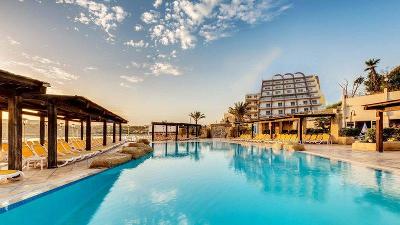 Ein luxuriösen Poolbereich unter einem sonnigen, leicht bewölkten Himmel im Familienurlaub Malta
