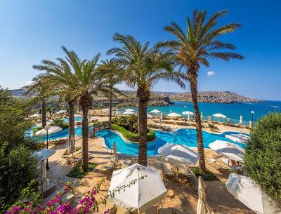 Ein Pool umgeben von Palmen und Meer im Familienurlaub Malta