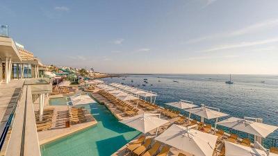 Ein Pool mit Sonnenligen und Meeresausblick im Familienurlaub Malta