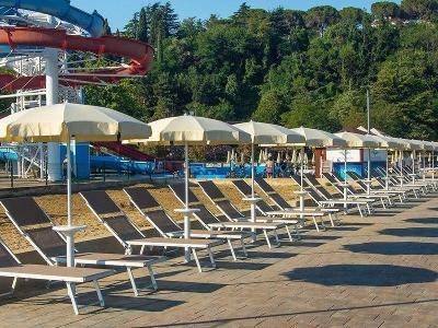Liegestühle mit Schirmen und Wasserrutschen im Hintergrund im Familienurlaub Kroatien
