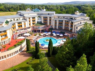 Hotel mit rundem Pool umgeben von Wald im Familienurlaub Ungarn