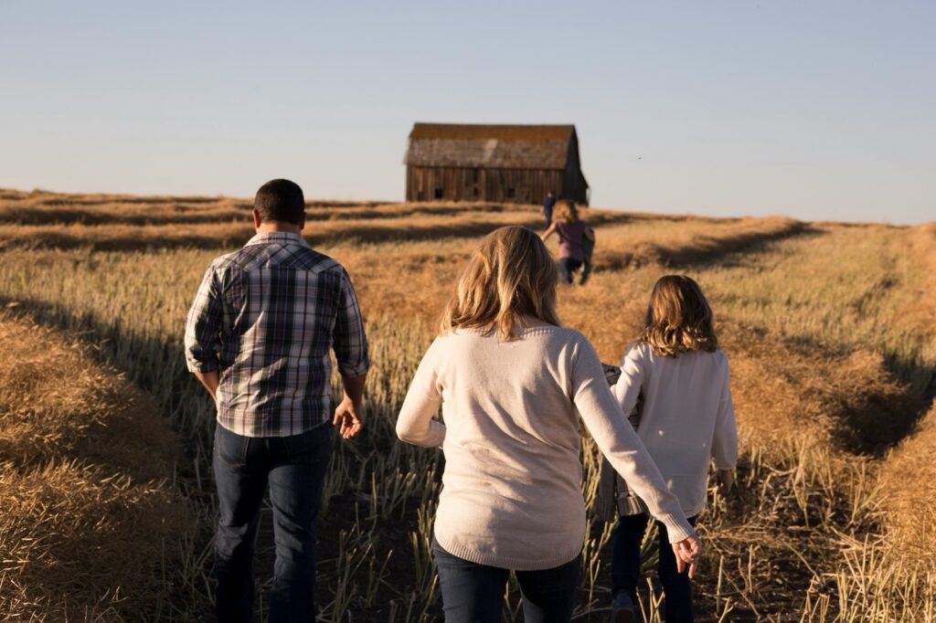 Wohin Kurzurlaub mit Kindern? Eine Familie auf einem Feld und im Hintergrund eine Scheune und blauer Himmel