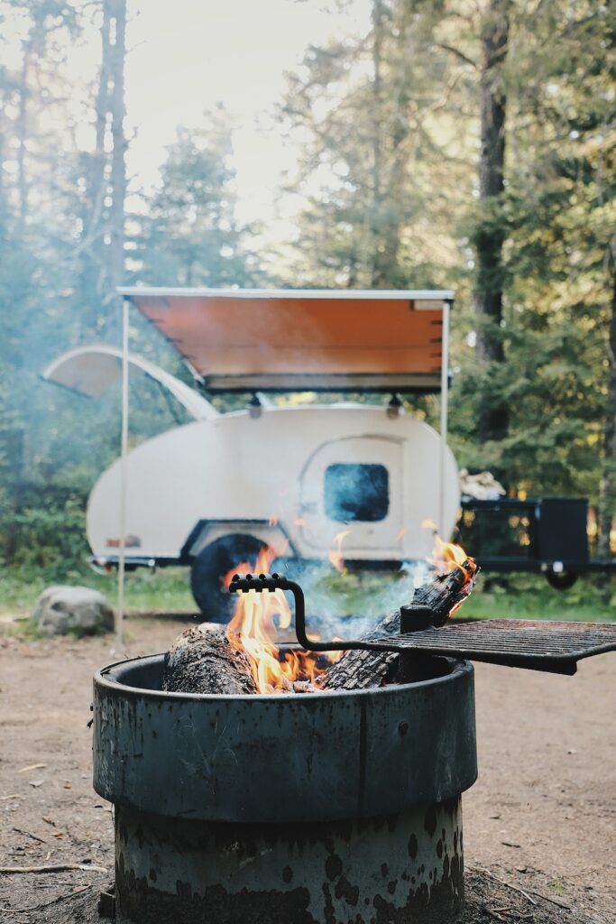 Reisen mit Kindern Tipps: ein Wohnmobil hinter einem Lagerfeuer