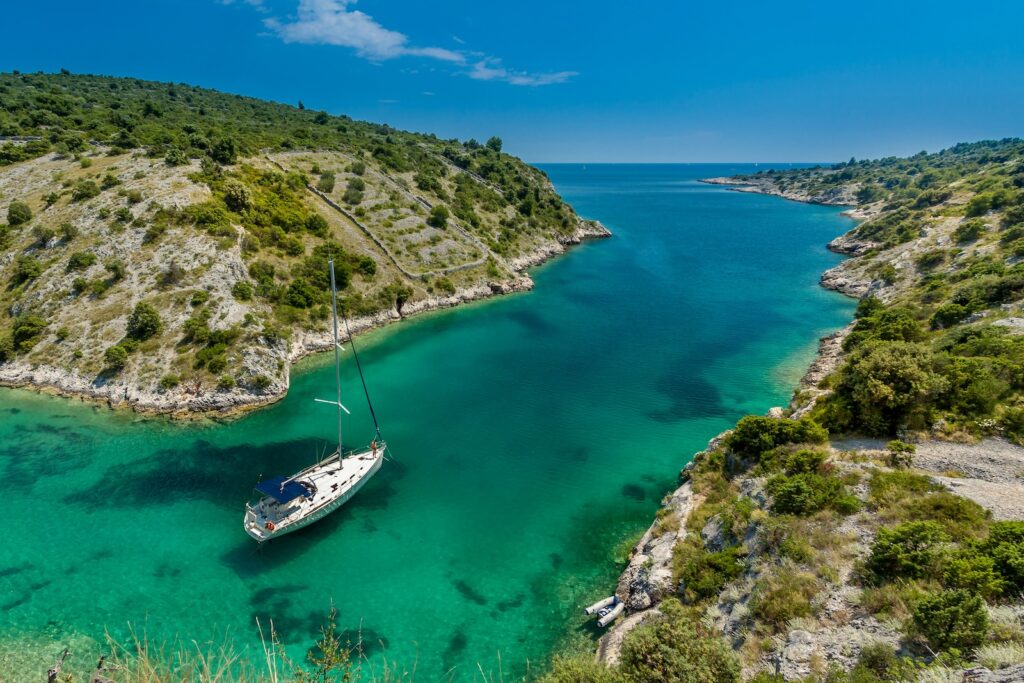 Urlaub mit erwachsenen Kindern in Kroatien bei einem flussartigen Meeresabschnitt auf dem ein Boot durch eine felsenartige Landschaft fährt