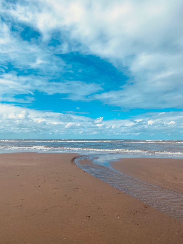 langer Strand an der Nordseeküste mit aufgewühlten Meer und weißen Wolken im wohin Kurzurlaub mit Kindern