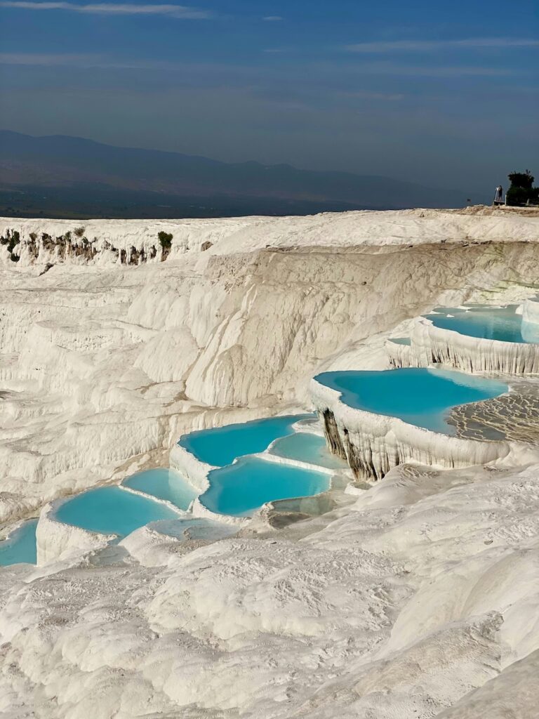 Die Kalkterrassen mit türkisfarbenen Wasser umrundet vom weißen Salz und Sonnenstand in Pamukkale