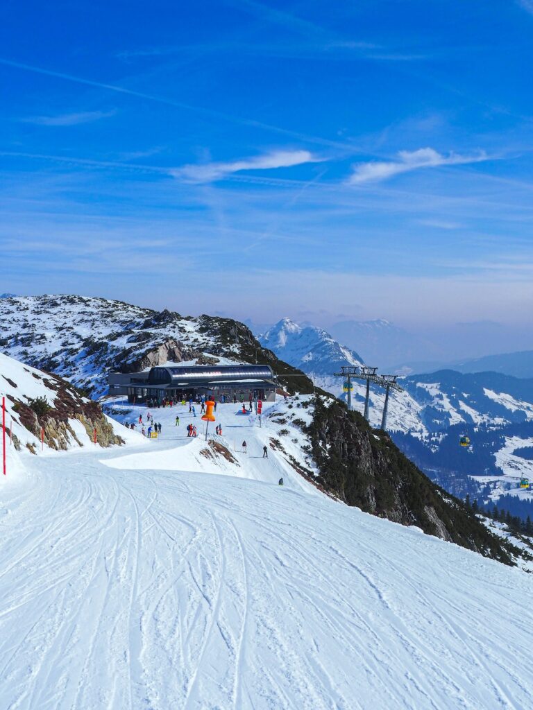 Wohin Kurzurlaub mit Kindern? Skigebiet in Österreich mit Skifahrern und einem Ausblick über die Schneelandschaft mit Bergen und blauen Himmel.